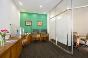 un ufficio con parete verde, scrivanie e sedie di Gamma Pachuca a Pachuca de Soto