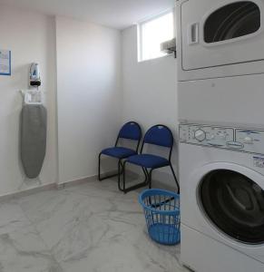 a laundry room with two blue chairs and a washing machine at One Silao in Silao