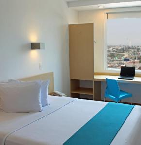 錫勞的住宿－錫勞One酒店，一间卧室配有一张床、一张书桌和一个窗户。