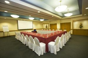 une salle de conférence avec une grande table et des chaises blanches dans l'établissement Fiesta Inn Ciudad del Carmen, à Ciudad del Carmen