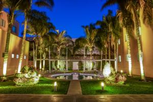 a courtyard with a pool and palm trees at night at Fiesta Inn San Luis Potosi Oriente in San Luis Potosí