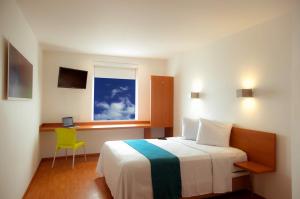 1 dormitorio con cama, escritorio y ventana en One Monclova en Monclova