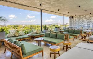 un restaurante con muebles verdes y ventanas grandes en Mex Hoteles, en Cancún