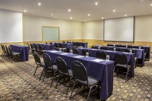 a conference room with blue tables and chairs and a screen at Fiesta Inn Centro Historico in Mexico City