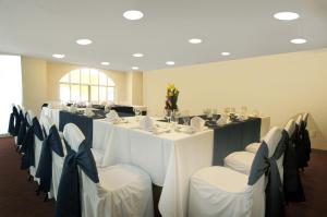 een kamer met een lange tafel met witte tafels en stoelen bij Fiesta Inn Toluca Centro in Toluca