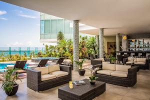 sala de estar con muebles de mimbre y piscina en Fiesta Inn Cancun Las Americas en Cancún