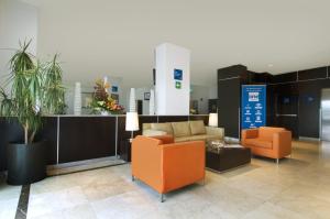 a lobby with two orange chairs and a couch at One Toluca Aeropuerto in Toluca