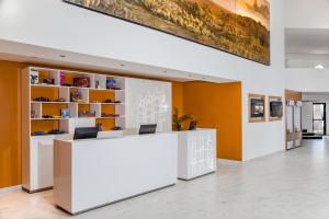 um átrio de escritório com uma recepção branca e paredes cor de laranja em Fiesta Inn Saltillo em Saltillo