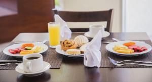 una mesa con platos de comida y un vaso de zumo de naranja en Gamma Tampico, en Tampico