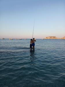 two people are standing in the water fishing at Buganvilla Sea View apts in Agia Pelagia