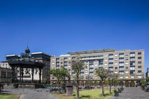 un parque con cenador frente a un gran edificio en One Guadalajara Centro Historico en Guadalajara