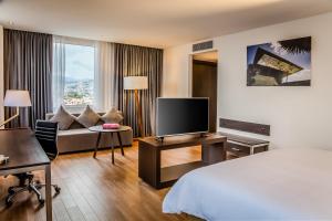 パチューカ・デ・ソトにあるFiesta Inn Pachuca Gran Patioのベッド、テレビ、ソファが備わるホテルルームです。