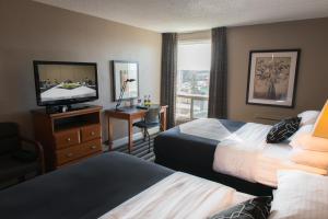 レジャイナにあるRoyal Hotel Regina, Trademark Collection by Wyndhamのベッド2台、薄型テレビが備わるホテルルームです。