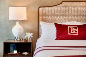 a bed with a red pillow and a lamp on a night stand at The Inn at Elon in Elon +13 photos