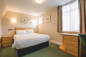 a small bedroom with a bed and a window at Wycliffe Hotel in Stockport