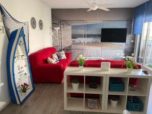 a living room with a red couch and a tv at Ático de lujo 90m de terraza y jacuzzi privado en Cabria, Almuñecar in Almuñécar