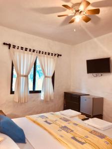 a bedroom with a bed with a ceiling fan and a tv at ALOHA LINA in Máncora