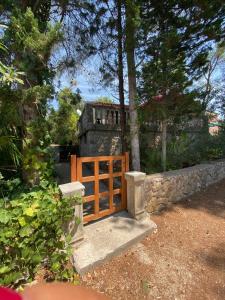 a wooden gate in a yard with a stone wall at Rustic Holiday Home - Artatore in Mali Lošinj