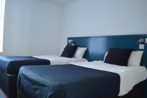 two beds in a hotel room with blue walls at Bell Gate House in Leicester