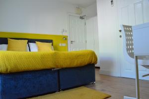 a bedroom with a bed with a yellow blanket at Bell Gate House in Leicester