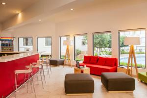 a living room with a red couch and a bar at Fiesta Inn Express Monclova in Monclova