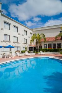 a pool in front of a hotel with chairs and umbrellas at Fiesta Inn Monclova in Monclova