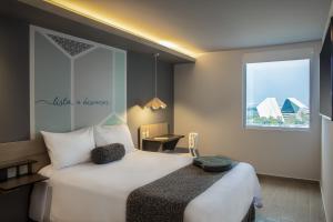 um quarto de hotel com uma cama grande e uma janela em One Monterrey Tecnologico em Monterrey