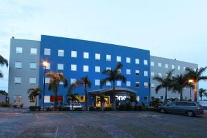 a large blue building with palm trees in a parking lot at One Cuernavaca in Cuernavaca