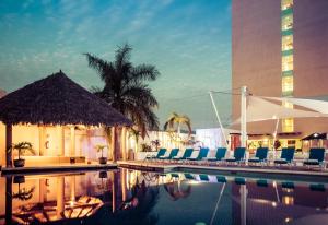 a swimming pool with chairs and a building at Fiesta Inn Tuxtla Gutierrez in Tuxtla Gutiérrez