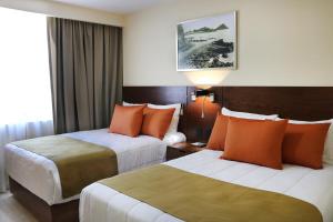 a hotel room with two beds with orange pillows at Gamma Mazatlan The Inn At Centro Historico in Mazatlán