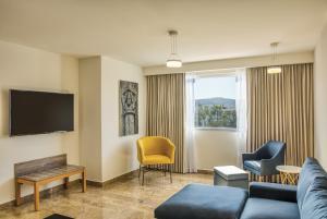 a living room with a couch and chairs and a tv at Fiesta Inn Guadalajara Periferico Poniente in Guadalajara