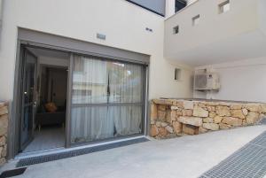een glazen deur van een huis met een stenen muur bij Brand new Cozy Basement Apartment in Argostoli