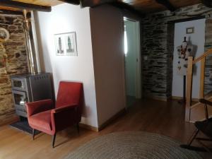 a living room with a red chair and a stove at Casa do Alto - Benfeita in Benfeita