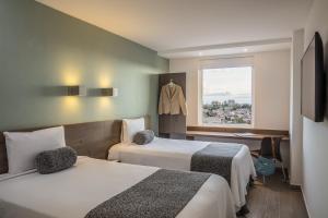 a hotel room with two beds and a window at One Puebla Serdan in Puebla +24 photos