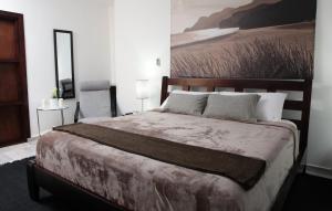 a bedroom with a large bed with a painting on the wall at Hotel Casa Jum in Santiago de los Caballeros