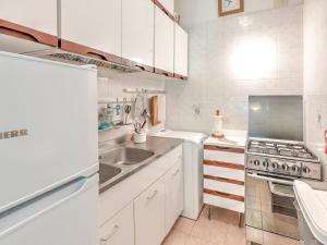 a white kitchen with a sink and a stove at Belvilla by OYO Le Mimose nr 11 in Punta Ala