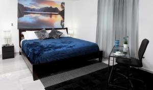 1 dormitorio con cama azul y escritorio en Hotel Casa Jum, en Santiago de los Caballeros