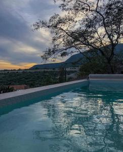 a swimming pool with a sunset in the background at Hotel de Piedra in Bernal