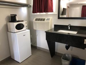 a kitchen with a refrigerator, sink and a microwave at Aquarius Motel in Perth