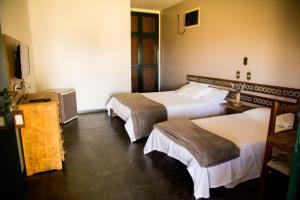 a hotel room with two beds and a television at Pousada Flor da Serra in Cruzeiro