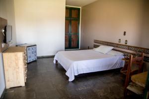 a bedroom with a white bed and a television at Pousada Flor da Serra in Cruzeiro