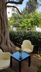 two chairs and a table in front of a tree at Kerynia Apartments in Paphos City