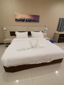 a bedroom with a large bed with white sheets and pillows at Hemingway Cottage 海明威度假屋 in Semporna