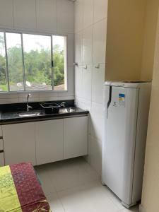 a kitchen with a white refrigerator and a window at Loft Juquehy in São Sebastião