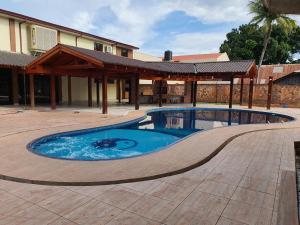 a swimming pool with a patio and a building at Tororoi Riberalta Apartments in Riberalta