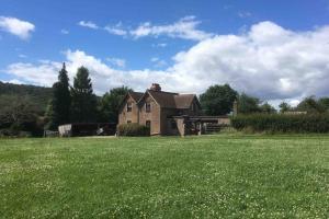 una casa con un gran campo de césped verde en Forest of Dean Country Cottage, en Mitcheldean