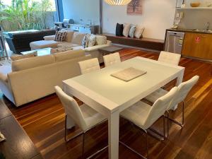 een woonkamer met een witte tafel en stoelen bij East On Byron in Byron Bay