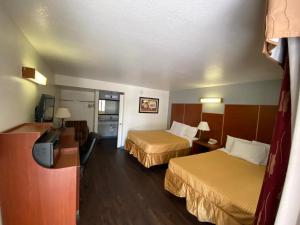 a hotel room with two beds and a television at Travelodge by Wyndham Albuquerque West in Albuquerque