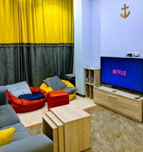 Marina Square Hostel في الغردقة: غرفة معيشة مع تلفزيون وأريكة وسرير
