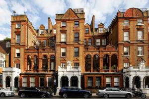 un grand bâtiment en briques avec des voitures garées devant lui dans l'établissement Exclusive Apartments South Kensington, à Londres